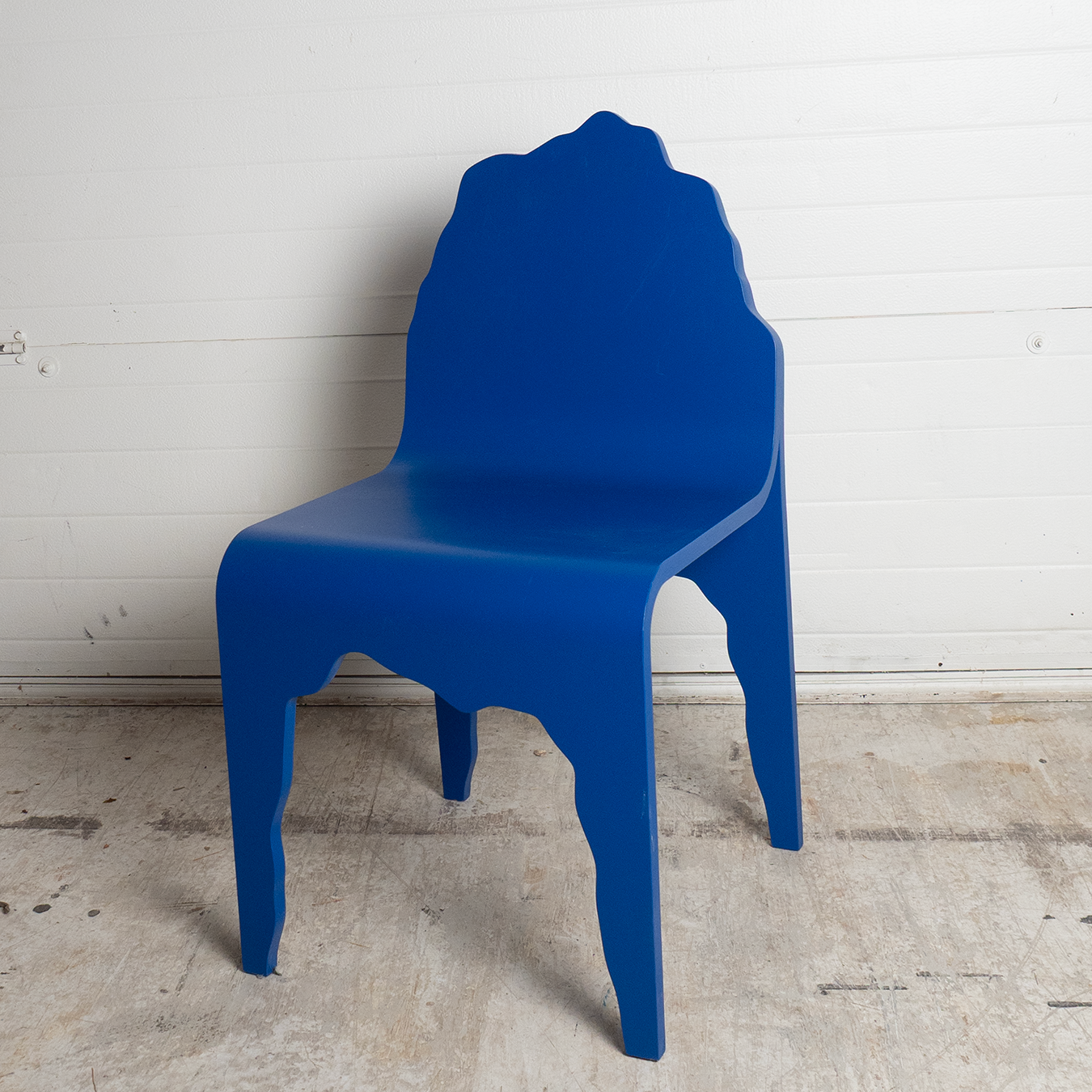 Blue chair against a white wooden paneled wall.